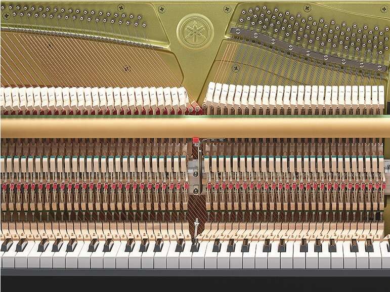 Close-up of an upright piano's internal mechanism with hammers, strings, and dampers visible behind the keyboard