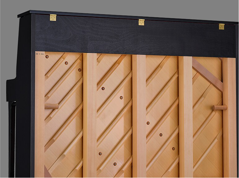 Upright piano with its front panel removed, exposing the wooden inner frame and diagonal braces.