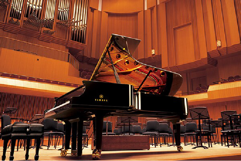 yamaha ydp-146r yamaha ydp-146wh 10 - mustore grand piano on a wooden concert hall stage with seats in the background and the lid raised to show strings inside, empty chairs nearby. - mustore