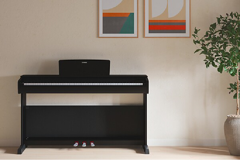 yamaha ydp-146r yamaha ydp-146wh 2 - mustore black digital piano on a stand against a beige wall, with two abstract framed prints above and a potted plant to the right. - mustore