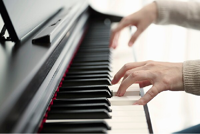 Close-up of hands playing a piano keyboard, fingers on black and white keys in motion.