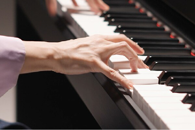 Yamaha YDP-S36B Close-up of hands playing a piano, fingers pressing white keys.