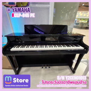 glossy black yamaha clp-845 pe digital piano on display in a showroom, keyboard visible with a purple/yellow promotional banner in the background. - mustore