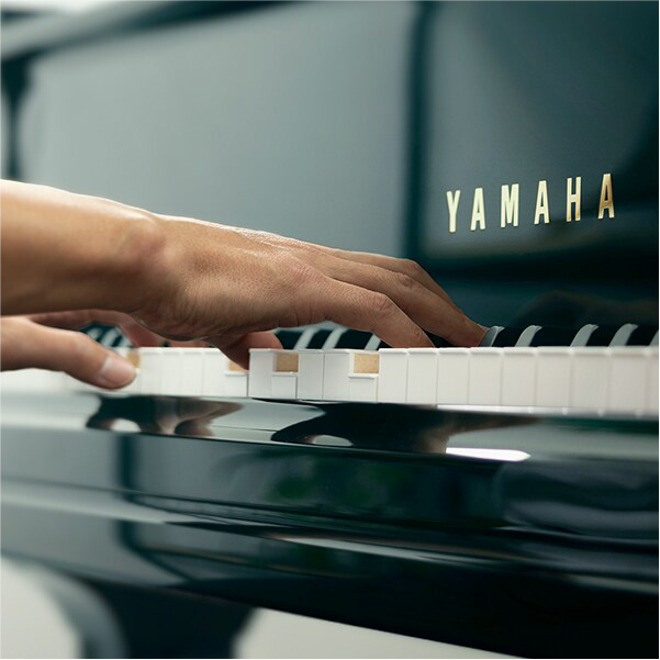 Close-up of hands playing a Yamaha piano keyboard.