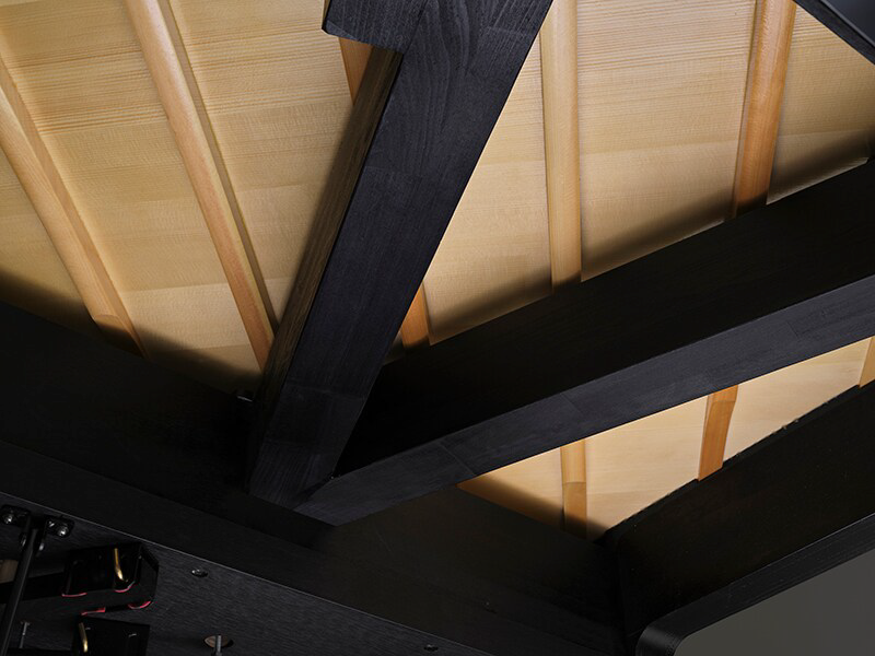 Dark wooden ceiling beams intersect over light wood ceiling planks, showing exposed structural framing.