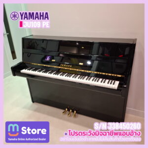 Black Yamaha upright piano with gold pedals in a showroom, backdrop of light walls and purple overlay branding on the top left.