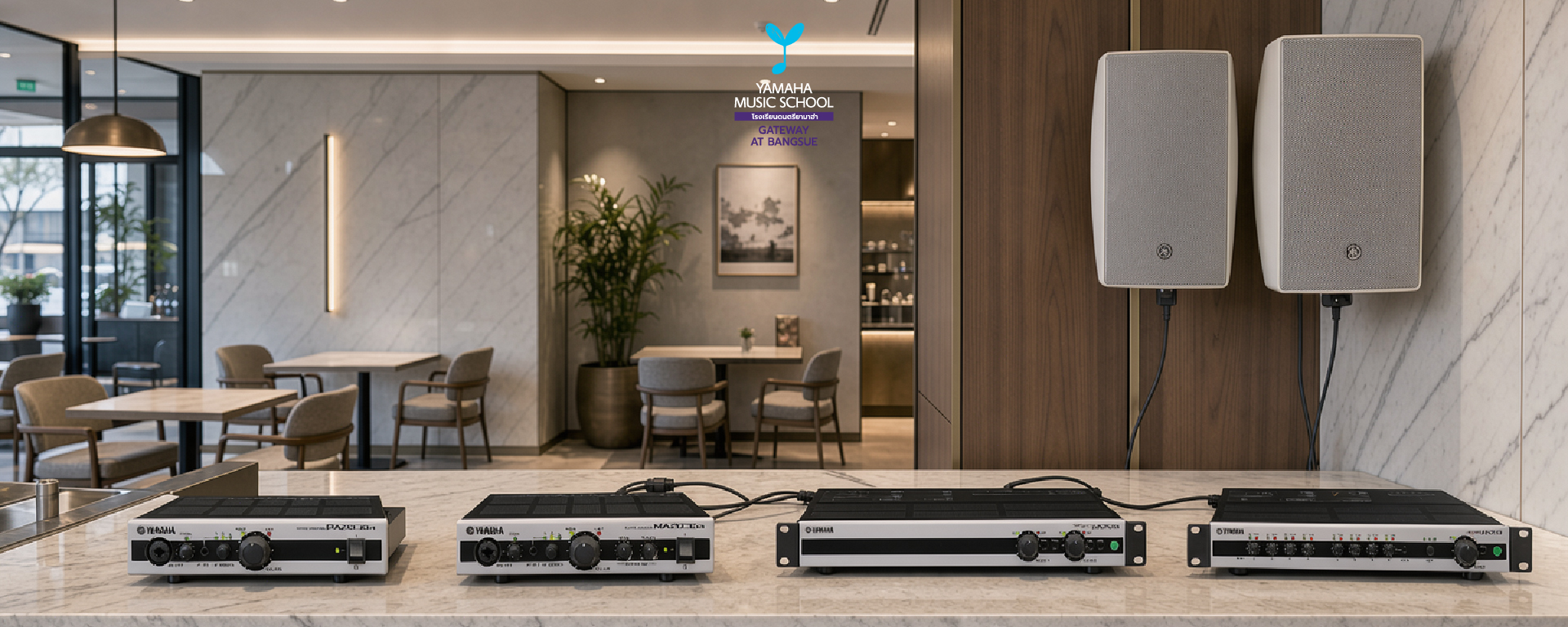 Four Yamaha audio amplifiers sit on a marble counter beneath two wall-mounted speakers in a modern reception area labeled Yamaha Music School.