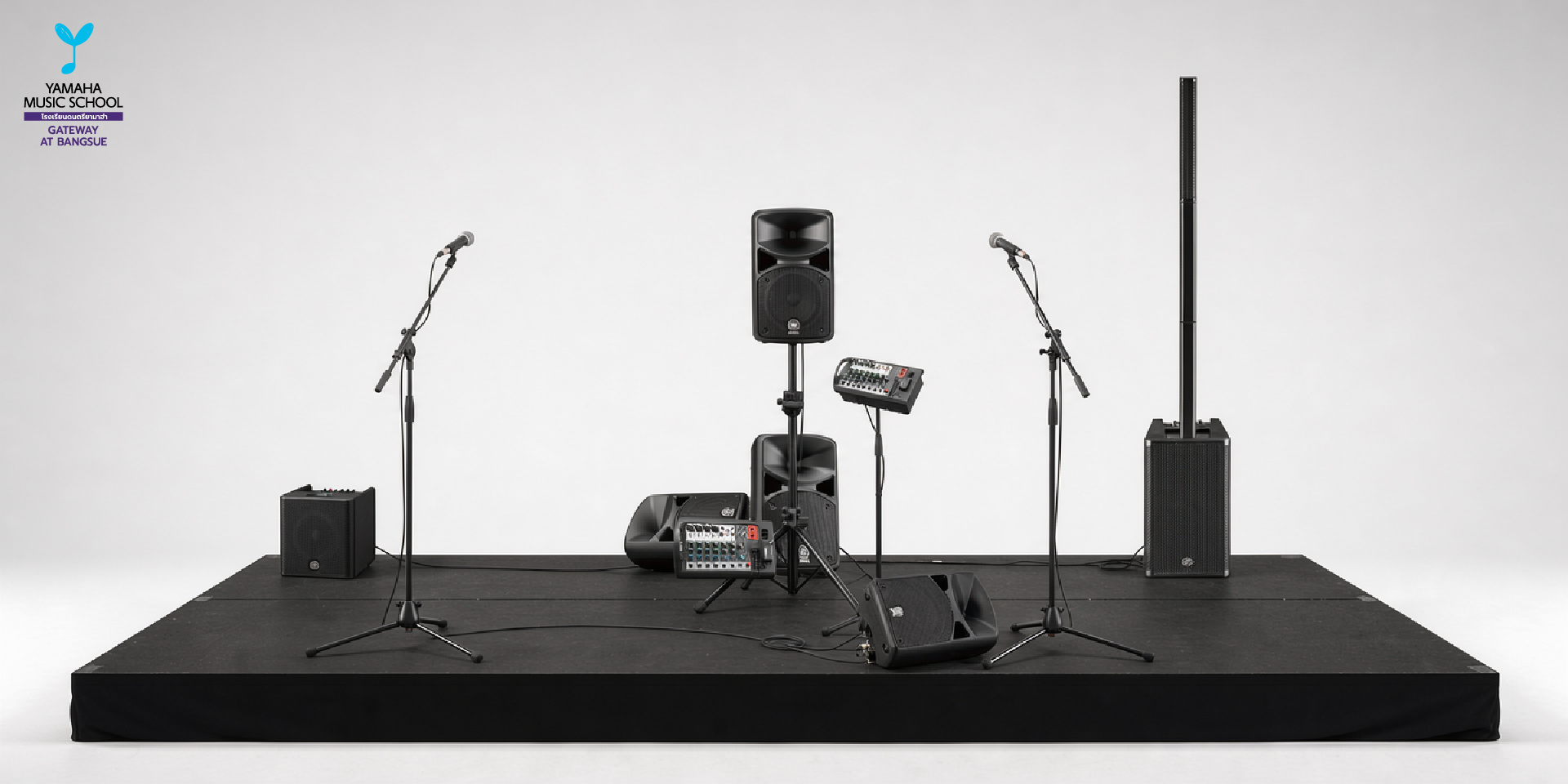 Stage setup with two microphones on stands, central speakers, and audio gear on a black platform; Yamaha Music School logo in the top-left corner.